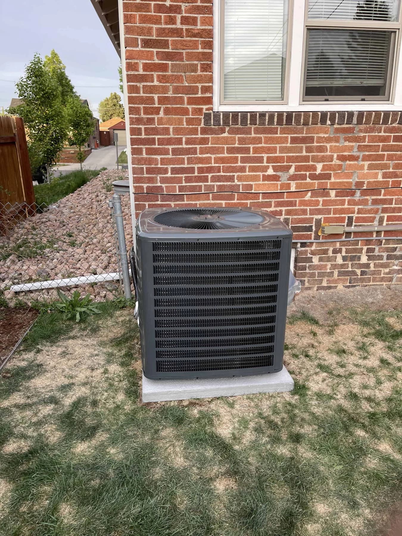 Outdoor cooling unit beside a brick wall